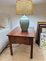 Side table with lamp on top, framed art nearby for scale