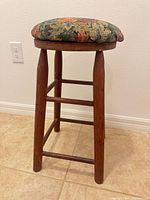 Full view of wooden stool showing height, leg design, and upholstered seat