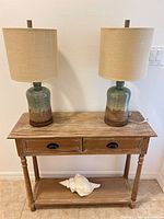 Console table with two lamps and conch shell front view