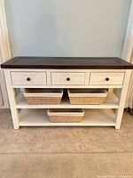Front view of whitewashed TV stand showing drawers, shelves and baskets
