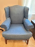 Front view showing entire blue wingback chair, upholstery, wooden legs