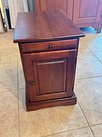 Full front view of end table closed showing wood finish, drawer and cabinet door