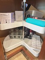View of lower lazy-susan shelf contents: milk jars, blender cups, hardware box, ice cube tray