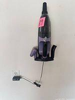 Vacuum mounted on wall charging cradle with power cord visible