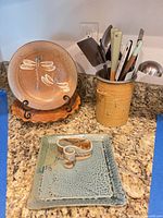 Group view of plate, pie dish, square dish, napkin holder, utensil crock with utensils