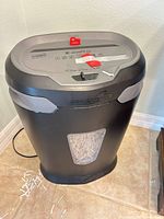 Full view of black Staples shredder with window showing shredded paper and power cord visible
