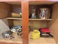 Cabinet shelves showing full group of cookware and rolling pin
