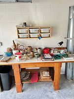 Overall view of workbench, wall shelf with bins and assorted pottery tools and supplies