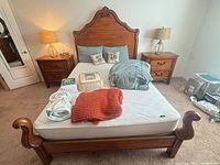 Overall view showing bed frame, mattress, nightstands, lamps, linens