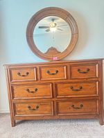 Front view of solid wood dresser with attached round mirror