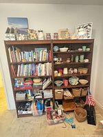 Full view of both bookcases loaded with books, pottery, baskets, decor