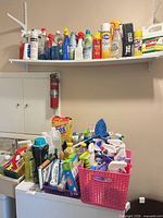 Full view of top shelf and washing machine loaded with assorted cleaning products