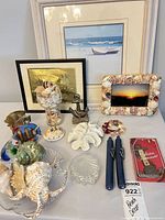 Group shot showing framed prints, photo frame, anchor, thermometer box, glass fish, starfish, coral, candles, shell dishes, goblet and dish of shells