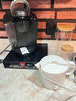 Coffee maker on K-cup drawer, electric kettle, two glass jars
