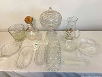 Group shot showing covered pedestal candy dish, pitcher, decanter, four relish trays, two bowls and pair of candle holders