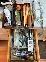 Drawer with trays containing knives, flatware, silicone spatulas, measuring spoons, cooking thermometer, can opener, Hamilton Beach electric slicer