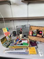 Full lot overview on desk showing calculator, numbering stamp, pens, rulers, labels pack, mesh rack and wicker basket