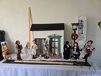 Line-up of 9 caroler figurines, wooden house facade, streetlamp and accessories