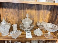 All eight clear pressed glass pieces on shelf