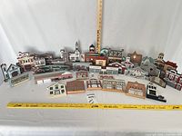 Full group of wooden village buildings displayed upright with yardstick for scale