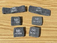 Six gray Arc'teryx sweatbands laid out: two long headbands, four wristbands