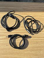 Three coiled black power cords on wood surface