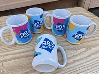 Five 98.5 OCEAN mugs top and side view