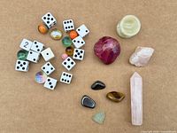 Group image of dice, marbles, tumbled stones, raw stones and rose quartz tower