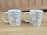 Front view of both mugs showing gold geometric pattern and handles