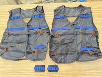 Pair of black mesh tactical vests with removable loop pads displayed on table