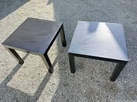 Two black square IKEA Lack tables on gravel surface
