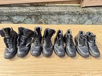 Four pairs of black leather Prada lace-up boots lined up on table
