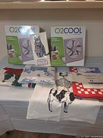 Group view of both boxed fans, two folded tablecloths and packaged kitchen towel