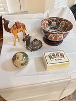 Group shot of all six items: bowl on stand, two camel figurines, bridge box, marble globe