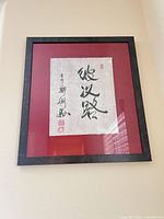 Full view of framed calligraphy showing red mat and black frame