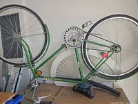 Full view of upside-down green John Deere bicycle showing frame, both wheels, handlebars, drivetrain