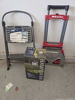 Group shot of step stool, folded hand truck, and boxed pathway light