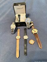 Group view of all seven watches laid out on blue surface