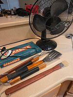 Lot overview showing table fan, Scrabble box, three BBQ tools, basting brush