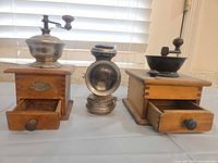 Full lot showing two coffee grinders with drawers open and carbide lamp between them
