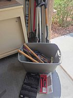 Overall lot showing long-handle garden tools, tote with contents