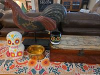 Group shot of rooster, map box, sugar-skull figurine, skull cup, brass bowl