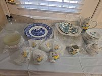 Entire lot on table showing tea set pieces, transferware plate, serving bowls