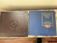 Front view of two album covers: blue slipcase with title and brown embossed Victor binder