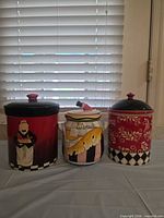Front view of three ceramic canisters with lids