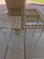 three cream metal plant stands with different top designs