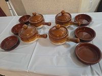 Group view of six lidded crocks and six ramekins on table