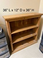 Front view of solid wood bookcase with three shelves and printed dimensions