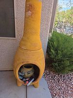 Full view of yellow terracotta chiminea standing against wall
