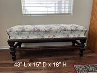 Full side view of floral upholstered bench on carved wood base